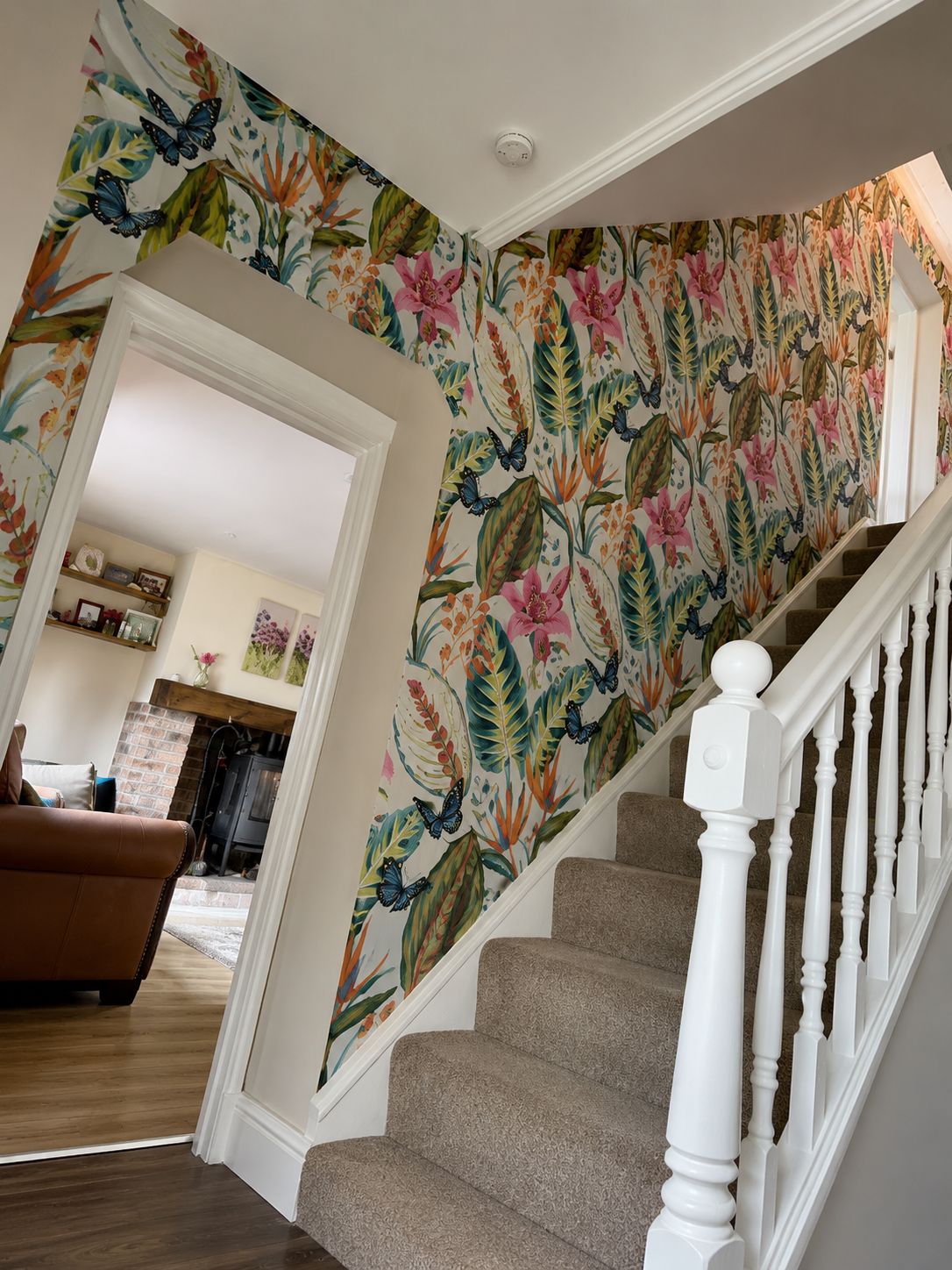Floral feature wallpaper under a staircase in an entrance hall